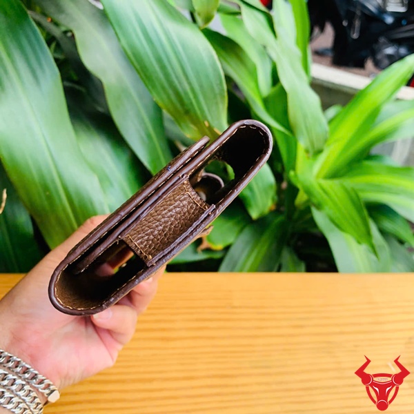 Bao Da Đeo Thắt Lưng OFAA19 - Cao Cấp Và Tiện Lợi Bao da đeo thắt lưng OFAA19 cao cấp, đặt trên bàn gỗ với cây xanh.