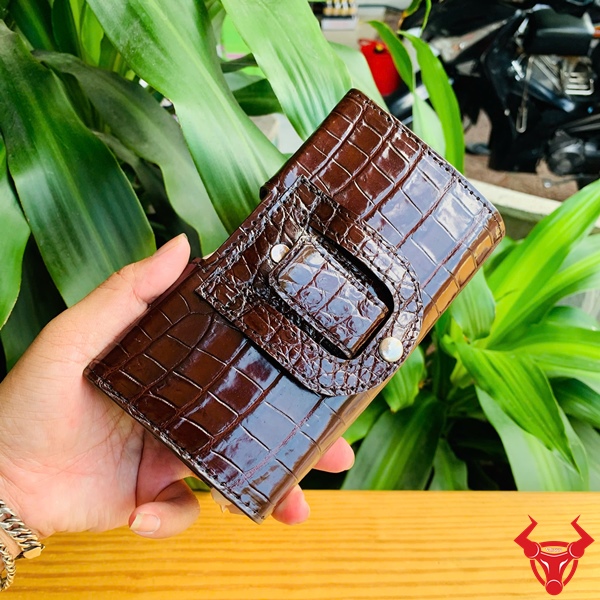 Bao Da Bụng Cá Sấu OFAA8 - Đẳng Cấp Quý Ông Tinh Tế Bao da bụng cá sấu OFAA8 đẳng cấp, đặt trên nền bàn gỗ với cây xanh.