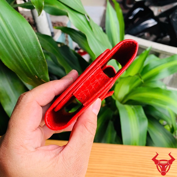 Bao Da Đeo Thắt Lưng Da Cá Sấu Màu Đỏ OFAA8 – Cao Cấp Sang Trọng Bao da đeo thắt lưng da cá sấu màu đỏ OFAA8, cầm trên tay, nền lá xanh, logo đỏ góc phải.