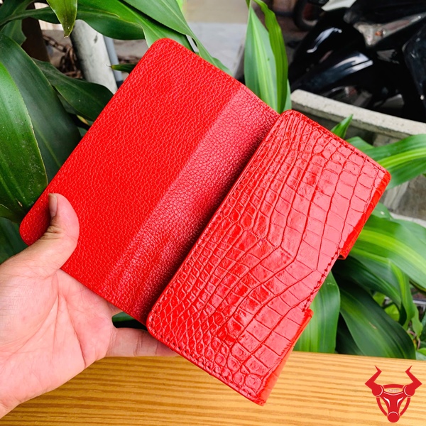 Bao Da Đeo Thắt Lưng Da Cá Sấu OFAA8 – Đẳng Cấp Cao Cấp Tuyệt Đỉnh Bao da đeo thắt lưng da cá sấu màu đỏ OFAA8, cầm trên tay, nền lá xanh, logo đỏ góc phải.