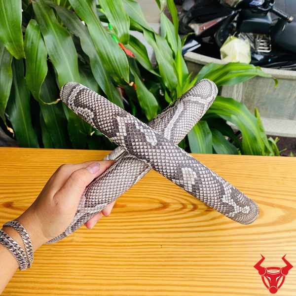 Phong Cách Thời Thượng Cho Xe Bọc vô lăng da trăn màu xám trắng họa tiết trăn, đường kính 33cm, đặt trên bàn gỗ, logo đỏ góc phải.