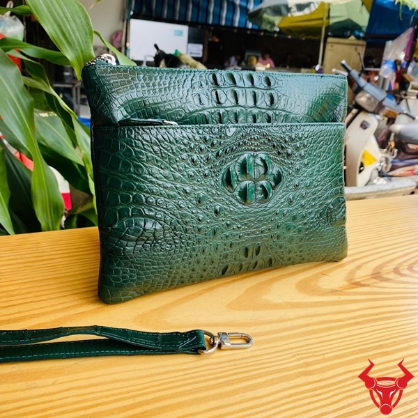 Clutch cầm tay da cá sấu thời thượng màu xanh lá.