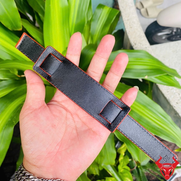 Dây Đồng Hồ Da Kèm Đệm Mặt Size 20 Dây đồng hồ da kèm đệm mặt size 20, màu đen, cầm trên tay, nền lá xanh, logo đỏ góc phải.