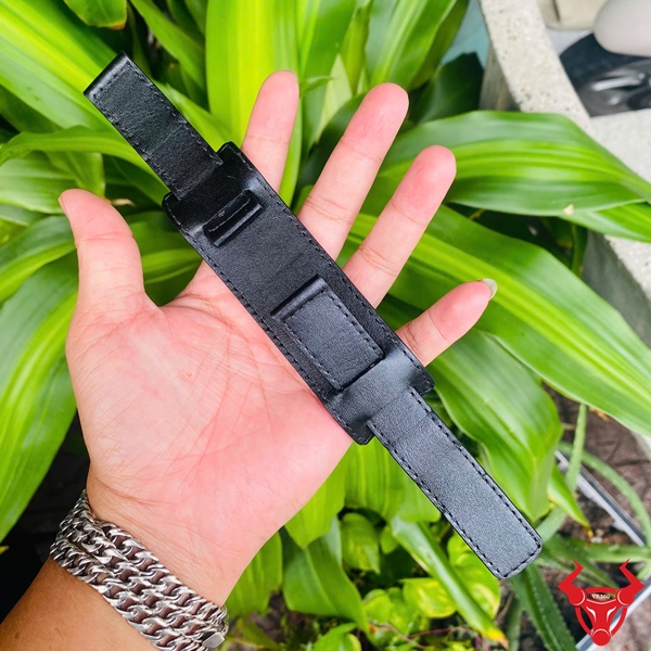 Dây Đồng Hồ Da Kèm Đệm Mặt Size 20 – Phong Cách Riêng Dây đồng hồ da kèm đệm mặt size 20, màu đen, cầm trên tay, nền lá xanh, logo đỏ góc phải.