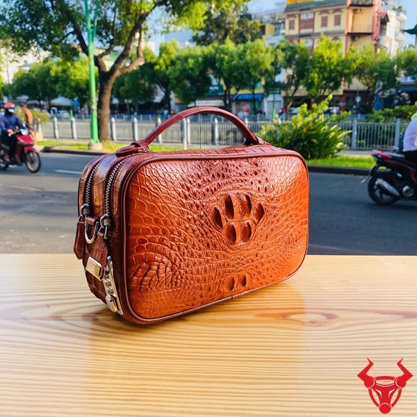 Túi xách tay golf màu nâu đỏ làm từ da cá sấu gù thật.