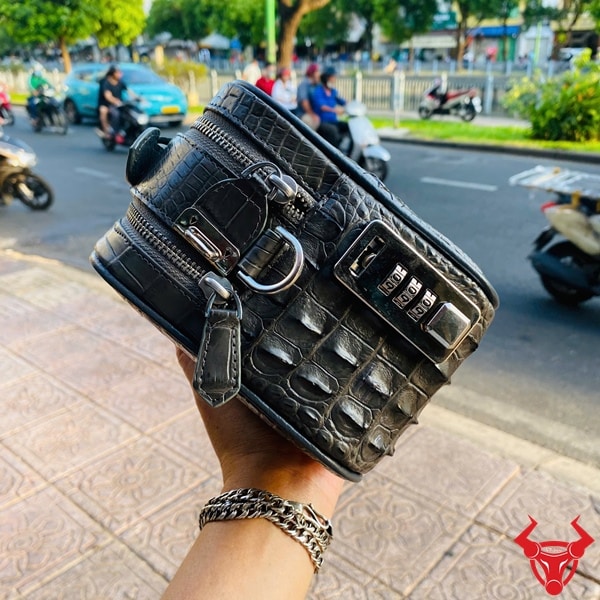 Túi golf màu xám làm từ da cá sấu gù thật trên tay người dùng.