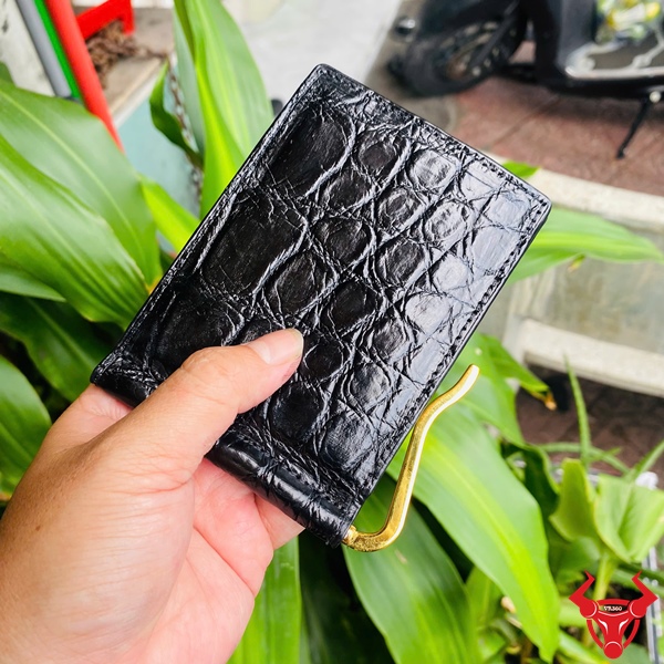Ví Da Bụng Cá Sấu VYA8 - Cao Cấp Với Thiết Kế An Toàn Ví da bụng cá sấu VYA8 cao cấp, trưng bày với nền cây xanh và xe máy.