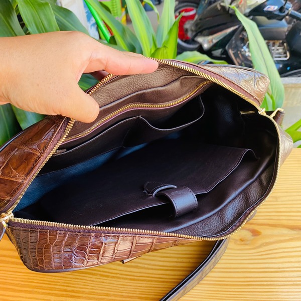 Phong cách thời trang đỉnh cao với cặp cá sấu Hình ảnh cặp da cá sấu CSA4 nâu đất, khóa cao cấp, sang trọng, trên bàn gỗ với cây xanh.