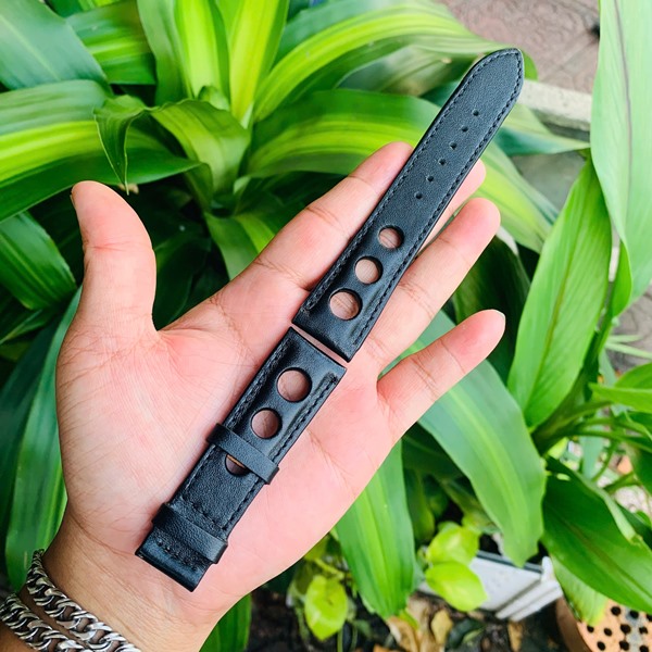 Phong cách thời trang với dây da bò thiết kế Hình ảnh dây đồng hồ da bò đen, lỗ thoát khí, thiết kế riêng, thẩm mỹ, trên tay với cây xanh.