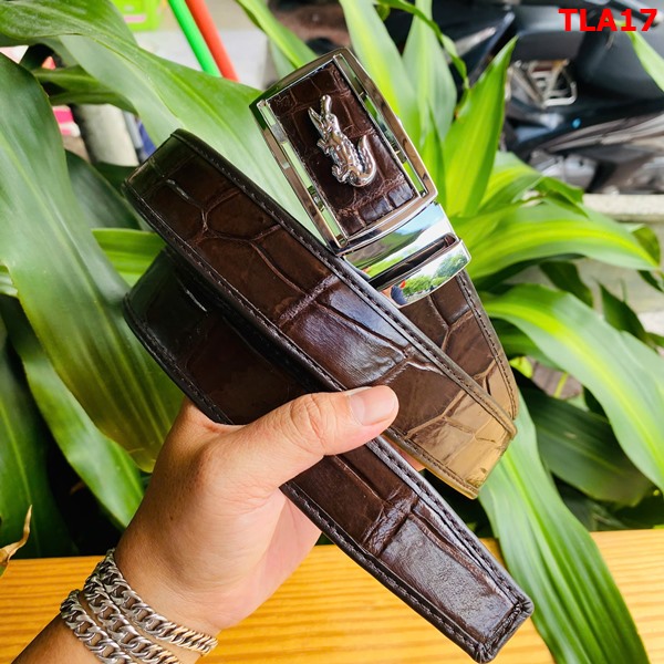 Thắt lưng FBA9B2 bền bỉ và chắc chắn Hình ảnh thắt lưng FBA9B2 da bụng cá sấu nâu đất, khóa kim loại, bền bỉ, trên bàn gỗ với cây xanh phía sau.