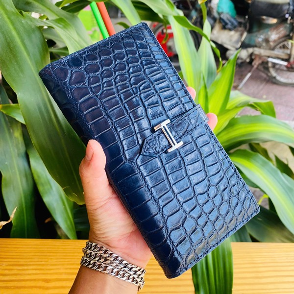 Đẳng cấp thời trang với ví da cá sấu FBA9B2 Hình ảnh ví da cá sấu Thái Lan FBA9B2, xanh đậm, khóa kim loại, cao cấp, trên bàn gỗ với cây xanh.