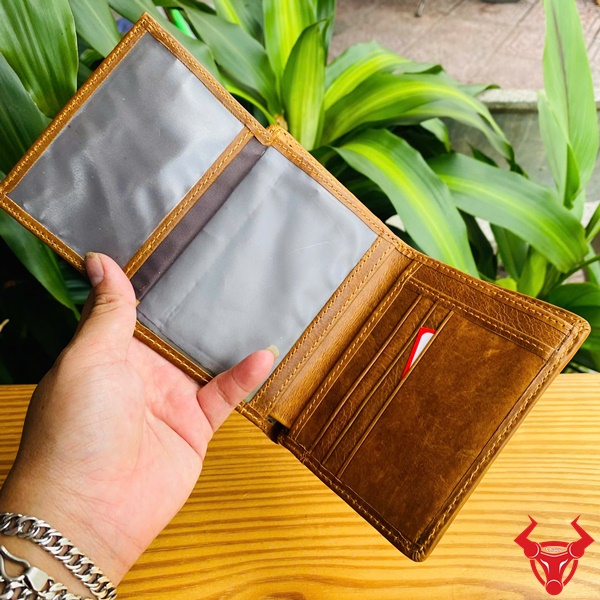 Ví Da Bò Nâu Bò - Thời Trang Đẳng Cấp Hình ảnh ví da bò nâu nhiều ngăn trên tay, nền cây xanh, thể hiện sự tiện ích và thời trang.