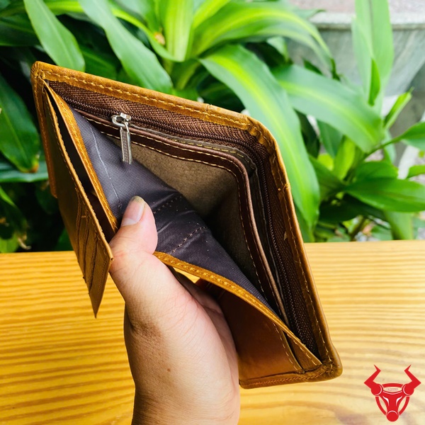 Ví Da Bò VDB10 - Tiện Lợi Mọi Lúc Mọi Nơi Hình ảnh ví da bò nâu nhiều ngăn cầm tay, nền cây xanh, nhấn mạnh sự tiện lợi và phong cách.