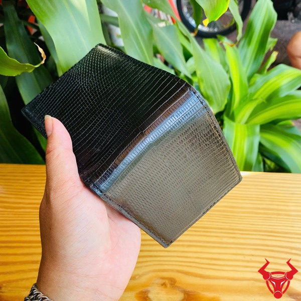 Ví Da Kỳ Đà VCA18 - Thời Trang Và Cá Tính Riêng Biệt Ví da kỳ đà VCA18 màu đen, thiết kế độc đáo, thể hiện cá tính riêng trước nền lá xanh.