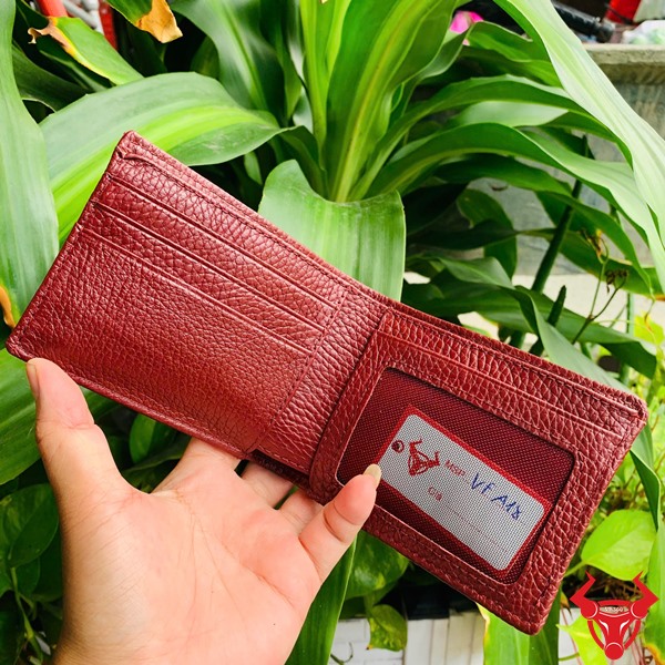 Ví da đỏ cam VFA18 – Cá tính mạnh mẽ, nổi bật giữa đám đông Một bàn tay cầm chiếc ví da đỏ cam với vân da kỳ đà rõ nét.