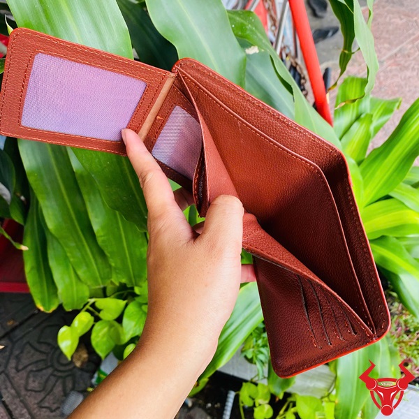 Ví Phối Màu Da Cá Sấu Độc Lạ Trong Từng Chi Tiết Ví ngang da cá sấu phối màu trắng-nâu, tay cầm, nền cây xanh và xe máy.
