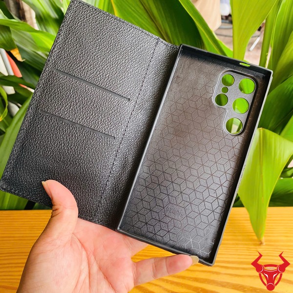 Phụ Kiện Bền Bỉ Sang Trọng Chắc Chắn Cao Cấp Đẳng Cấp Bao Da S24 Ultra Cá Sấu Gù Lưng Đen Hình sản phẩm bao da S24 Ultra da cá sấu gù lưng đen, cầm tay trên bàn, nền lá, thể hiện sự chắc chắn.