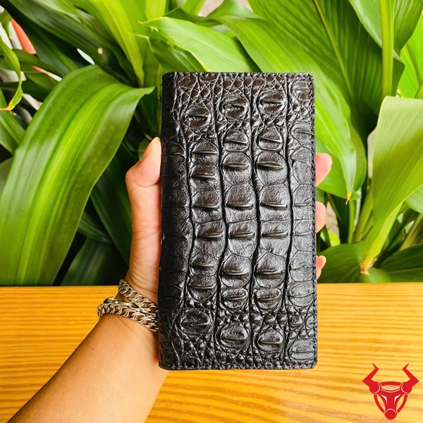 Phụ Kiện Sang Trọng Cao Cấp Bền Bỉ Chắc Chắn Đẳng Cấp Ốp Lưng S24 Ultra Da Gai Cá Sấu Màu Đen Ảnh bao da S24 Ultra da cá sấu đen, cầm nghiêng với nền lá, nhấn mạnh sự cao cấp và chắc chắn.