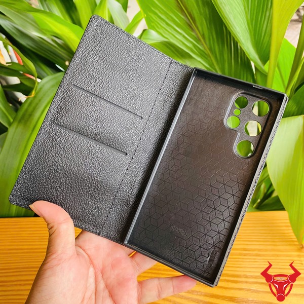 Phụ Kiện Sang Trọng Chắc Chắn Cao Cấp Bền Bỉ Đẳng Cấp Ốp Da Cá Sấu S24 Ultra Màu Đen Ảnh bao da S24 Ultra da cá sấu đen, cầm nghiêng với nền lá, nhấn mạnh sự sang trọng và bền bỉ.