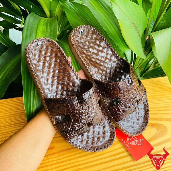 Dép Da Cá Sấu Chữ H Đế Cao Su Thoải Mái Thời Trang Cao Cấp Êm Chân Hình dép chữ H da gai tay cá sấu đế cao su, trên tay trước lá xanh, thể hiện sự thoải mái và thời trang.
