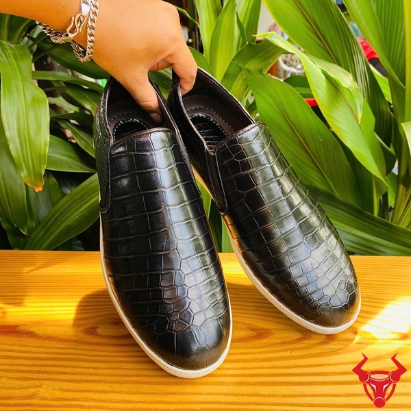 Cao Cấp Thời Trang: Giày Thể Thao GCS25 Năng Động Sang Trọng Hình đôi giày thể thao màu đen da cá sấu cao cấp, đặt trên bàn gỗ nền lá xanh.