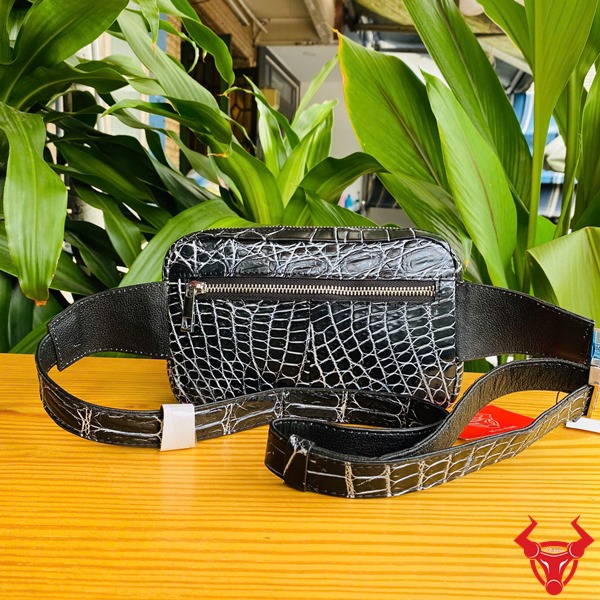 Túi Đeo Bụng Cá Sấu TTL06 Đen Năng Động Thời Trang Đa Năng Ảnh túi đeo bụng TTL06 da cá sấu đen, đặt trên bàn với nền lá, nhấn mạnh sự năng động và đa năng.