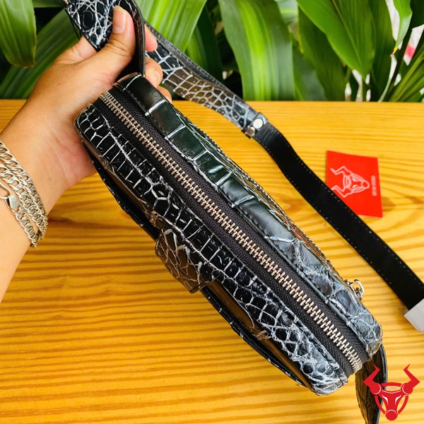 Túi Đeo Bụng Da Cá Sấu TTL06 Đen Năng Động Đa Dụng Thời Trang Ảnh túi đeo bụng TTL06 da cá sấu đen, đặt trên bàn với lá xanh, nhấn mạnh sự năng động.