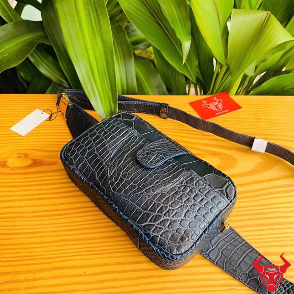 Túi Đeo Bụng Da Cá Sấu TTL06 Xanh Navy Thời Trang Năng Động Đa Năng Ảnh túi đeo bụng TTL06 da cá sấu xanh navy, đặt trên bàn với lá xanh, nhấn mạnh sự thời trang và năng động.