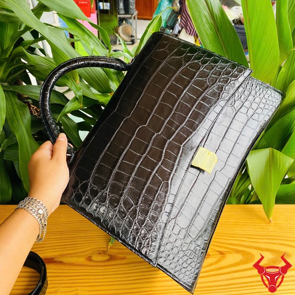 Túi Xách Da Cá Sấu TTL07 Đen Thời Trang Đẳng Cấp Quý Phái Cao Cấp Hình ảnh túi xách TTL07 da cá sấu đen size lớn, trên bàn gỗ với lá xanh, thể hiện sự đẳng cấp.