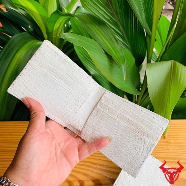 Ví Mini VGA8 Da Cá Sấu Trắng – Sản Phẩm Thời Trang Cao Cấp Đẳng Cấp Chiếc ví mini trắng mộc da cá sấu VGA8 trên tay, bên cạnh lá cây xanh tươi.