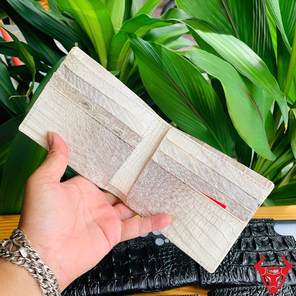 Thời Trang Sang Trọng: Ví Nam Cao Cấp VCA8 Da Cá Sấu Bạch Tạng Đẳng Cấp Hình ảnh ví da cá sấu trắng bạch tạng cao cấp được cầm, bên dưới là các ví da đen nâu, nền lá xanh.