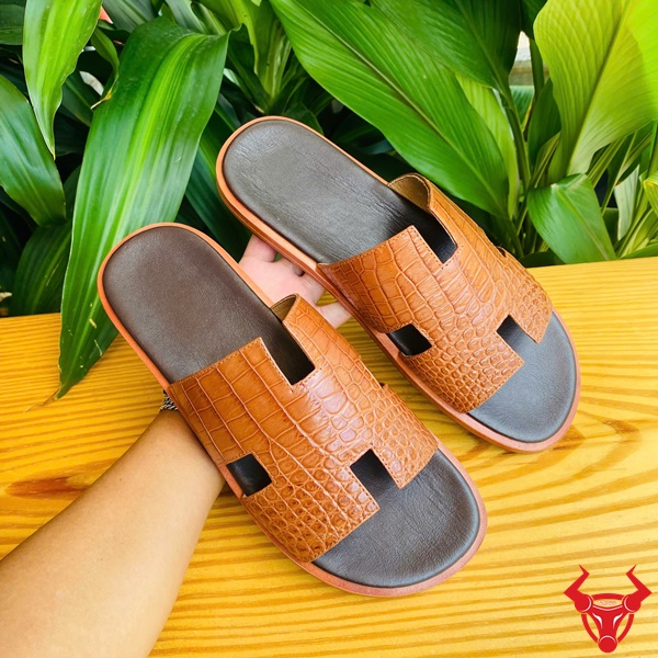 Cao cấp thời trang dép da cá sấu, bền đẹp và êm chân vượt trội. Sản phẩm dép DJA8 da cá sấu chữ H màu nâu nhạt size 41 trên bề mặt gỗ.