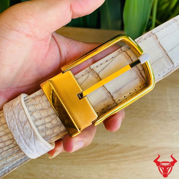 Đẳng Cấp Nam Giới Với Thắt Lưng Cá Sấu Bạch Tạng Lịch Lãm Ảnh cầm thắt lưng da cá sấu bạch tạng với khóa kim lấp lánh trước nền thực vật xanh, đại diện cho đẳng cấp.