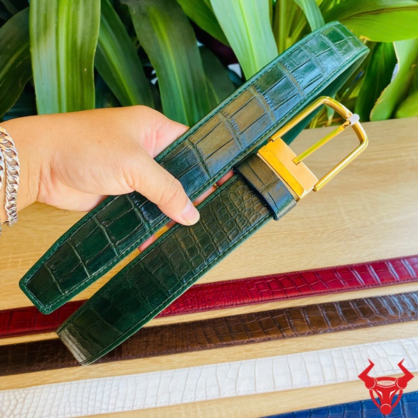 Thắt Lưng Cá Sấu Xanh Lá - Biểu Tượng Cao Cấp Cho Quý Ông Thắt lưng da cá sấu xanh lá bản rộng với khóa kim vàng, được cầm tay trước nền lá cây xanh mướt, tượng trưng cho phong cách cao cấp.