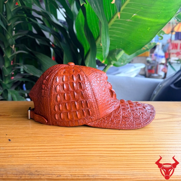 Mũ Da Cá Sấu NOA4 Màu Nâu Đỏ Thời Thượng Mũ lưỡi trai da cá sấu gù NOA4 màu nâu đỏ thời thượng với bề mặt da tự nhiên nổi bật.